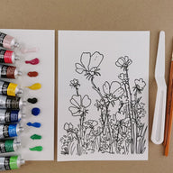 Art supplies including paint tubes and a floral drawing on a brown background
