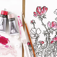 Acrylic paint tubes and a brush next to a floral drawing on a white background