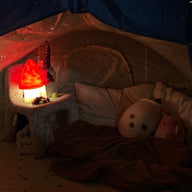 Children's play area with a tent, lamp, and toys in a dimly lit room.